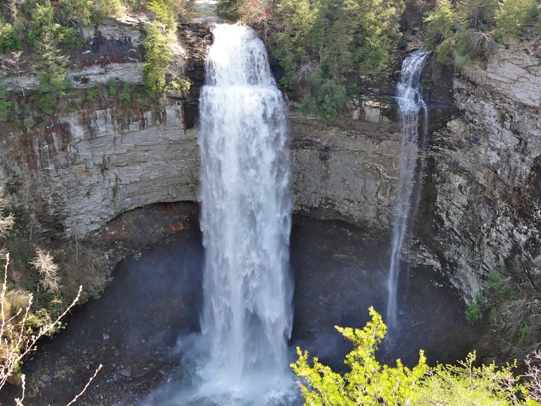 A high waterfall plunging into a shaded plunge pool
